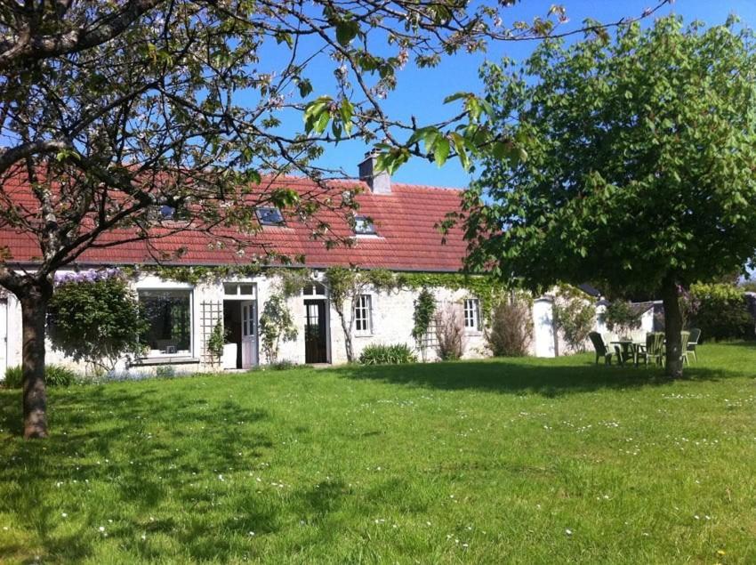 une maison blanche avec un toit rouge sur une cour verdoyante dans l'établissement Maison familiale de campagne à 10 min d Utah Beach, à Sainte-Mère-Église