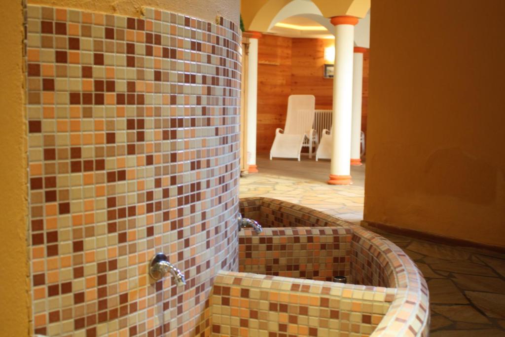 a bathroom with a tub made out of mosaic tiles at Le Rocher Hotel in Champoluc