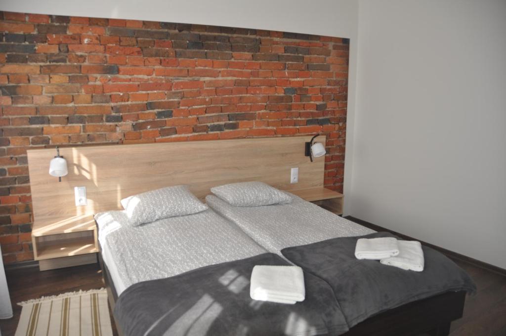 a bedroom with a bed and a brick wall at Apartamenty Przy Starówce in Zielona Góra