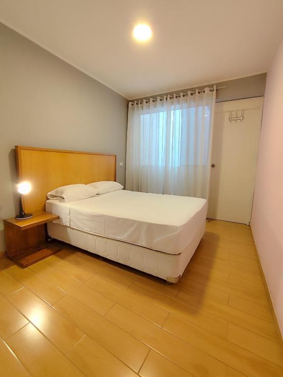 a bedroom with a large white bed and a window at Apartamento Limas Airport in Lima