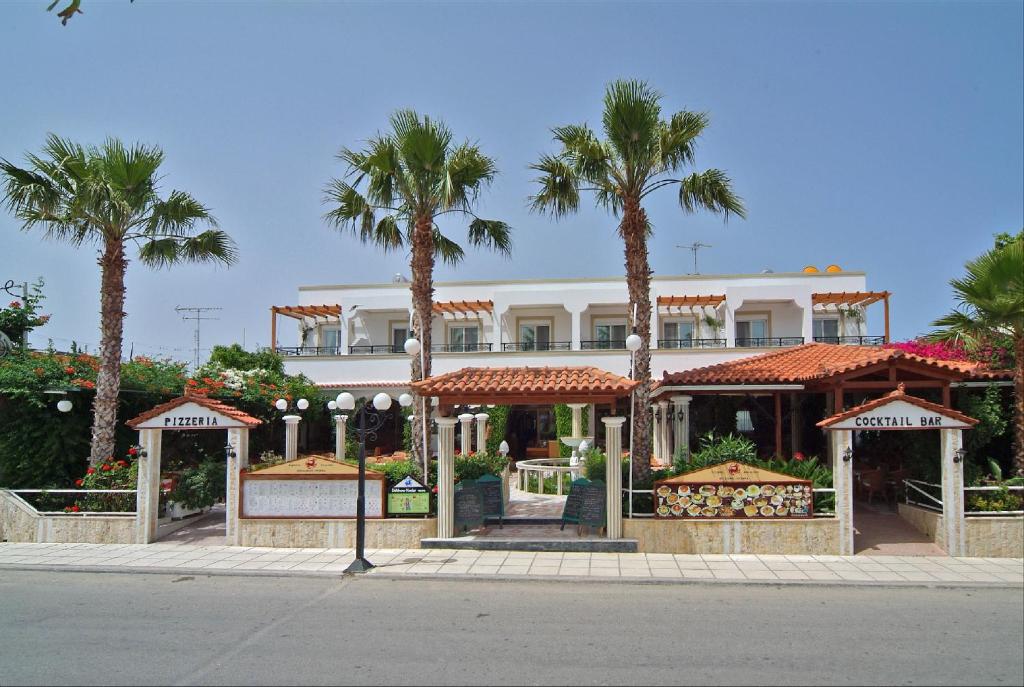 a large white building with palm trees in front of it at Sagittarius Apartments in Tigaki