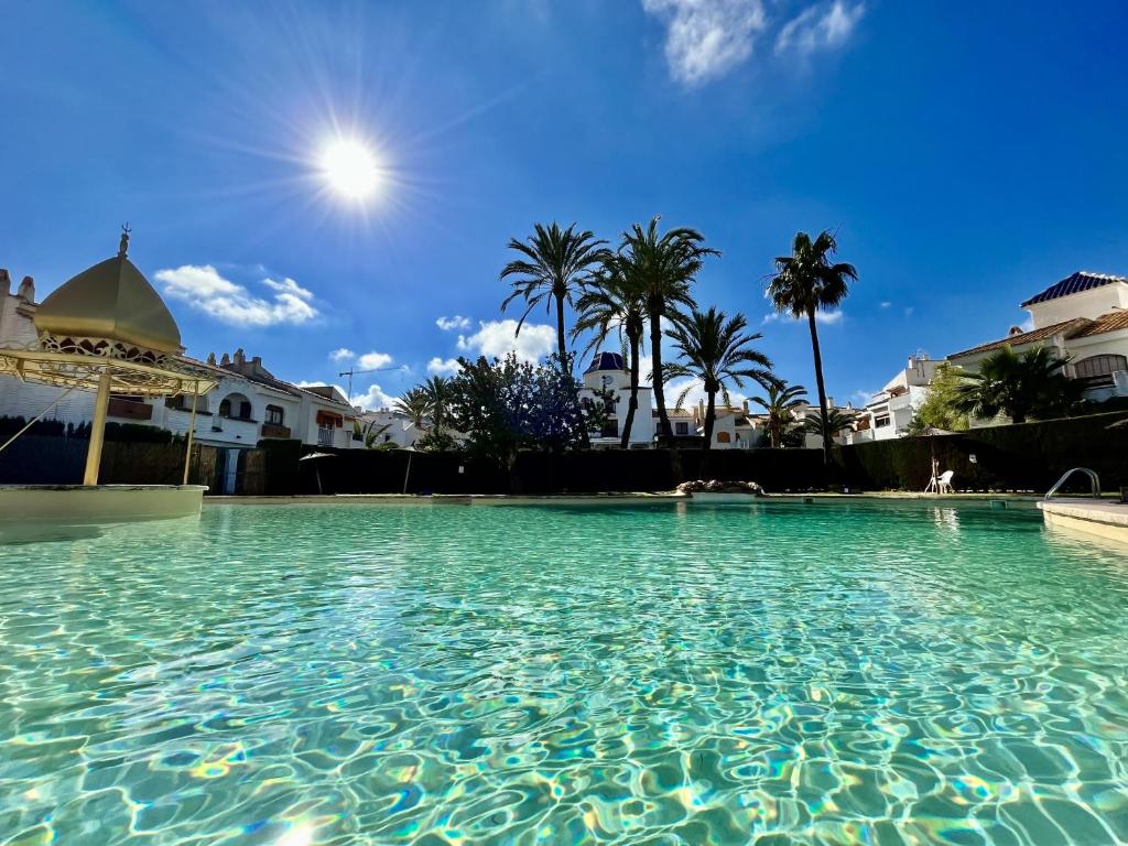 einen Pool mit Palmen im Hintergrund in der Unterkunft Duplex en la playa in Puerto Marino
