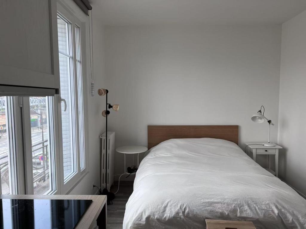 une chambre avec un lit et une grande fenêtre dans l'établissement Studio Plein Soleil Seine, à Paris