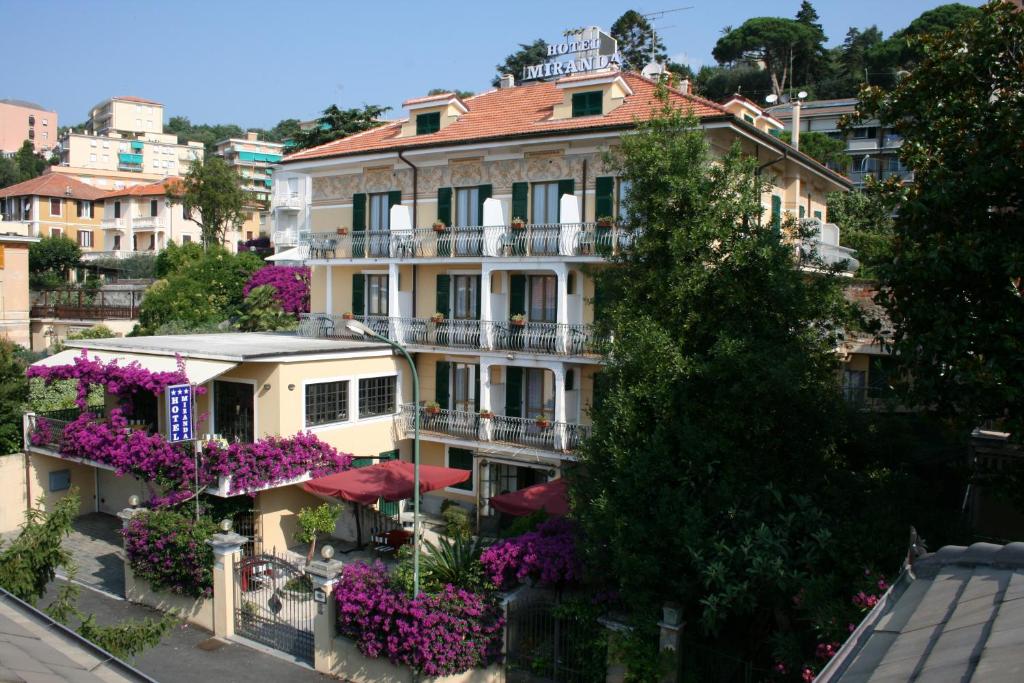un edificio con sombrillas y flores delante de él en Hotel Miranda, en Varazze