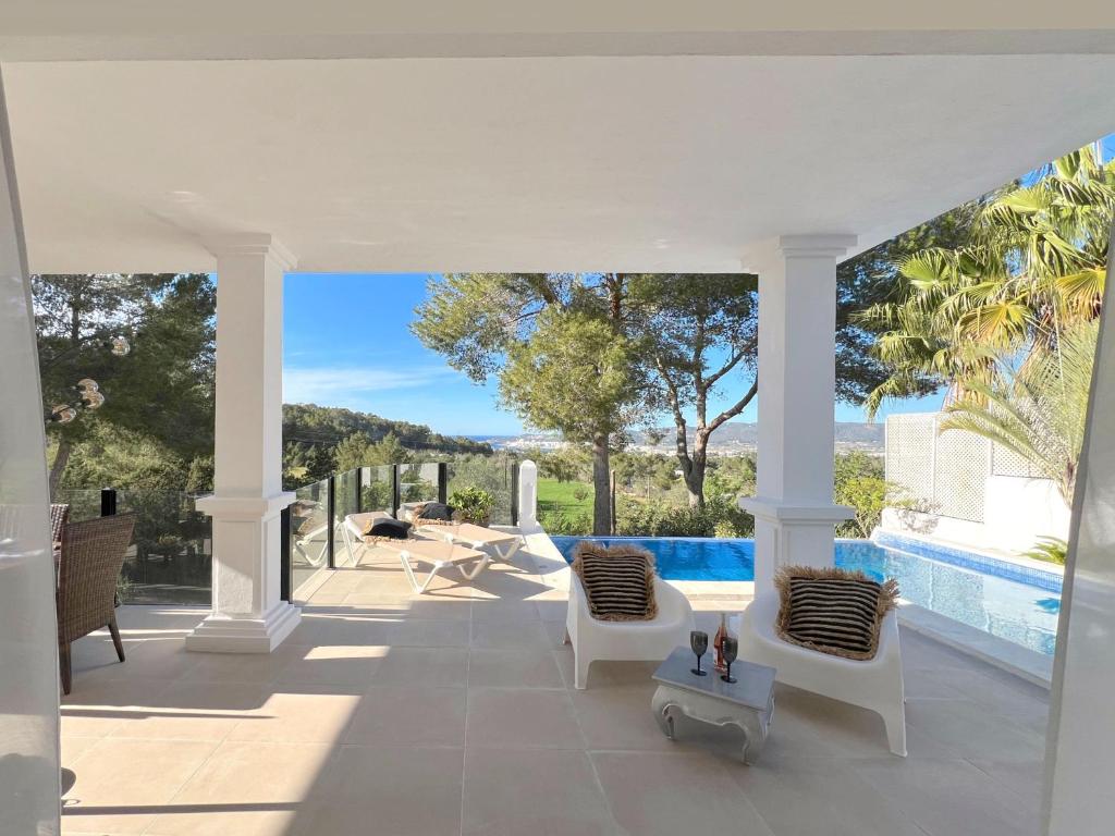 une terrasse avec des chaises blanches et une piscine dans l'établissement Villa Sunset Bay, à San José