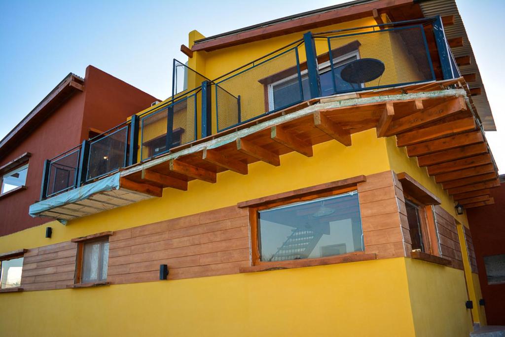 un edificio amarillo con balcón en la parte superior en Turismo Aparts Cabaña 4, en Villa Giardino