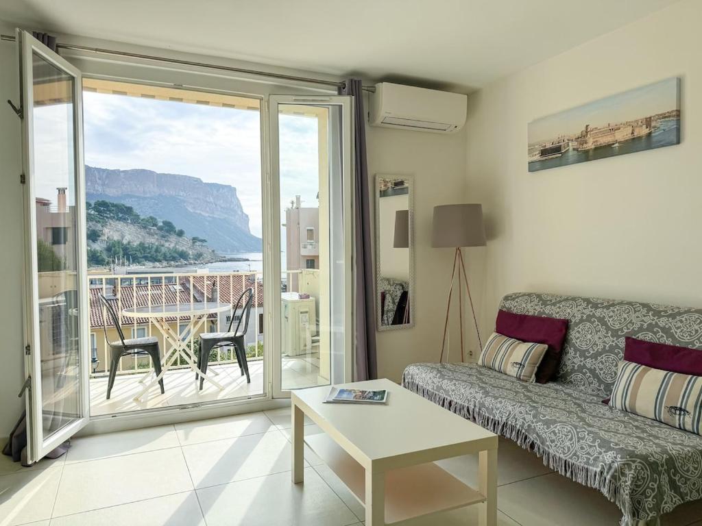 d'un salon avec un canapé et une table ainsi que d'un balcon. dans l'établissement Petit Cocon - Parking - Climatisation - Wifi, à Cassis