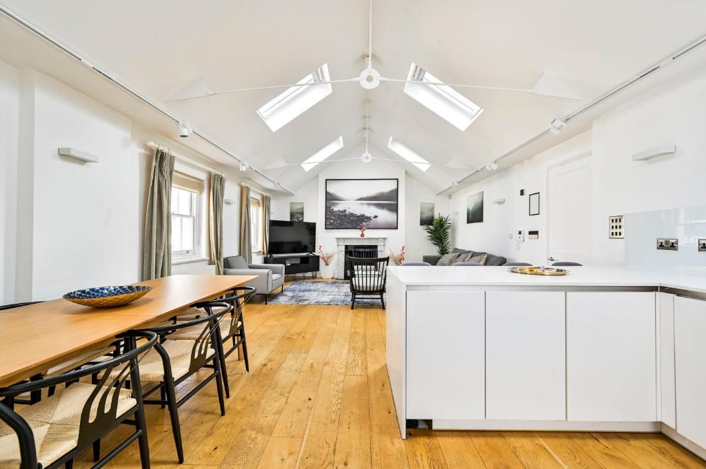 a kitchen and living room with white cabinets and a wooden table at Spacious Fitzrovia Apartment 3 Bed in London