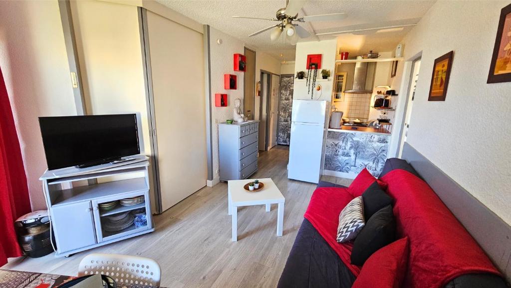 un salon avec un canapé rouge et une cuisine dans l'établissement Séjour détente entre étang et mer à la Couladère, au Barcarès