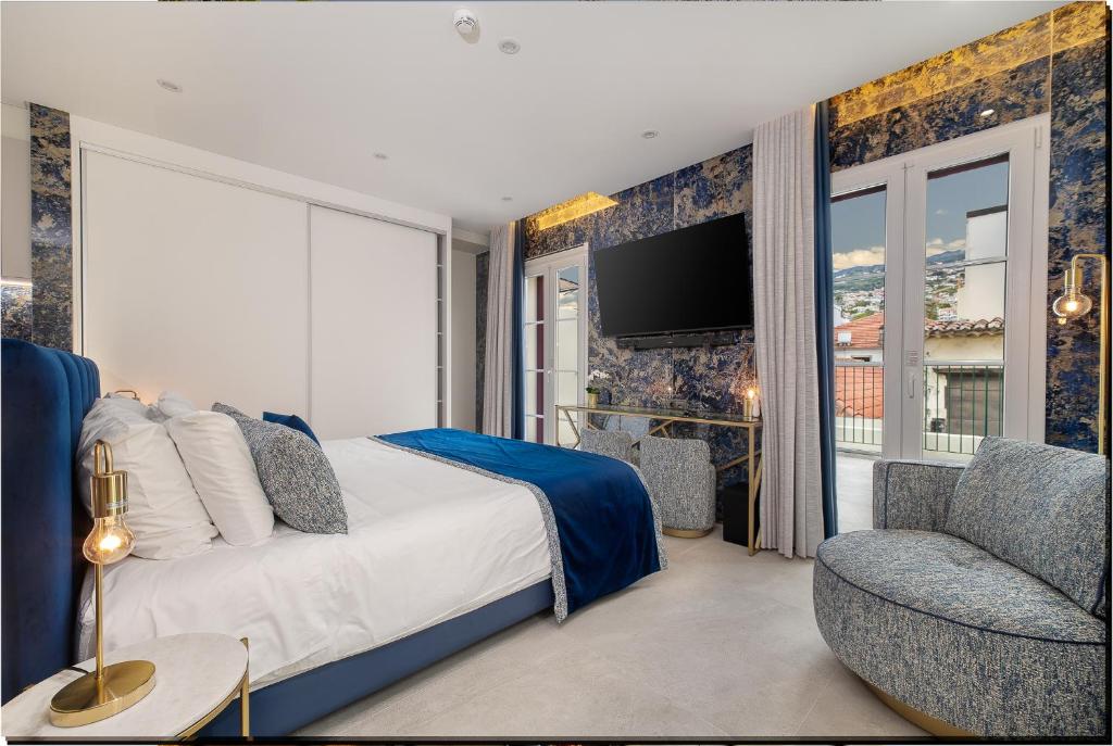 a bedroom with a bed and a chair and a television at Safira Suites 302 in Funchal