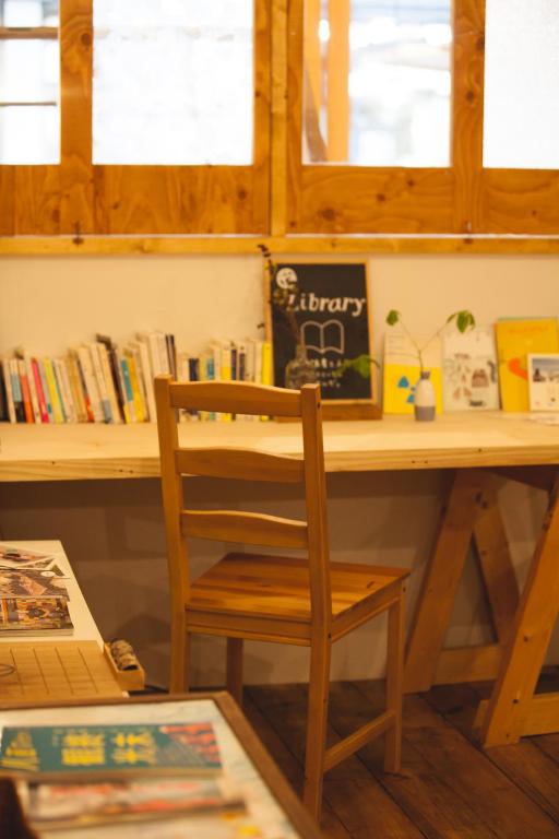 a wooden desk with a chair next to a table with books at Guest House MARUYA in Atami