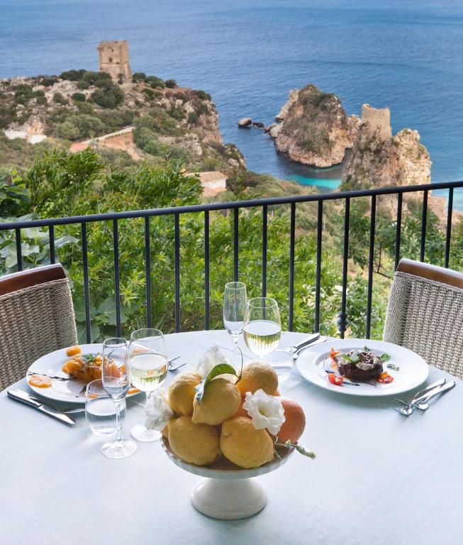a table with a bowl of food and glasses of wine at Torre Bennistra in Scopello