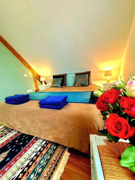 une chambre avec un lit avec des draps bleus et des roses rouges dans l'établissement La Bergeronnette Maison105 m2 3 Chambres, à Bellebrune