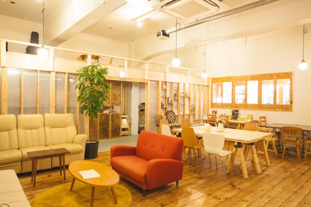 a living room with a couch and a table and chairs at Guest House MARUYA in Atami