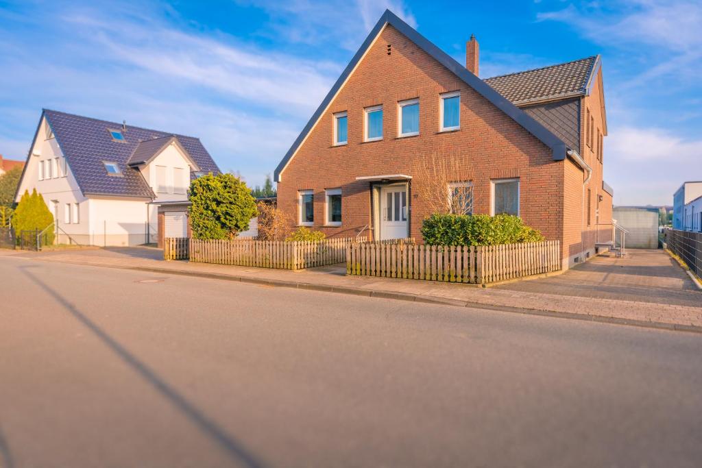a brick house with a fence on a street at Sleeping Home - Red House - Großes Haus für Gruppen mit 2 Wohnungen - 15 Betten - 2 Küchen - Parkplätze - Self Check-in in Bielefeld