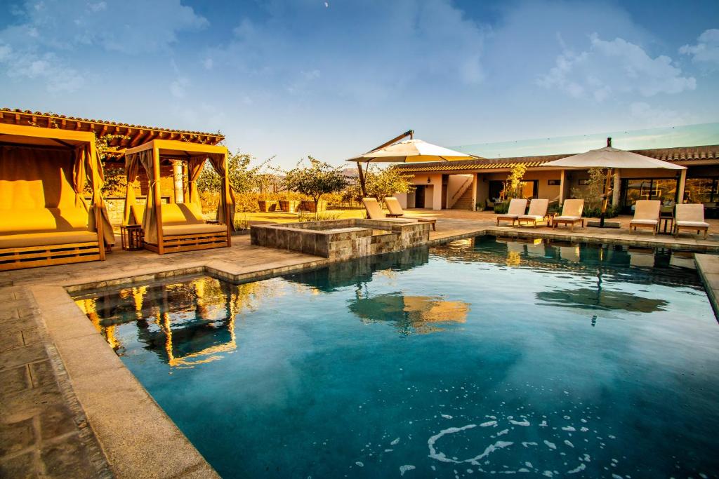 バジェ・デ・グアダルーペにあるHotel Flores de Sal-Valle de Guadalupeの椅子と家のあるプール