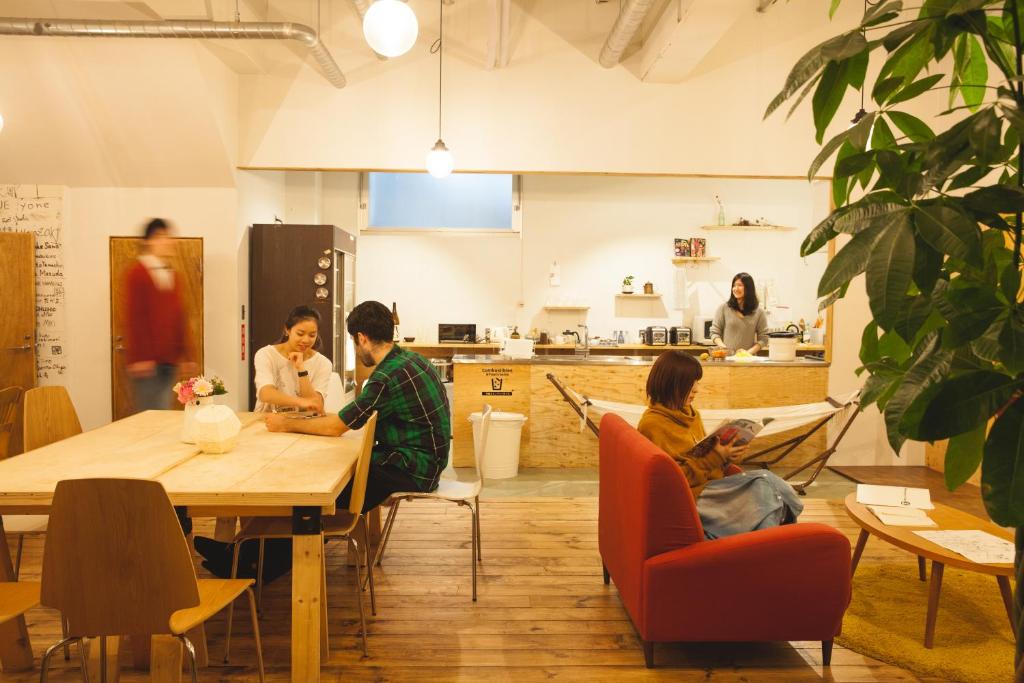 a group of people sitting around a table in a room at Guest House MARUYA in Atami