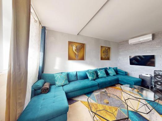 un salon avec un canapé bleu et une table en verre dans l'établissement Le Donjon Port Nature 5 Village Naturiste Cap d'Agde, au Cap d'Agde