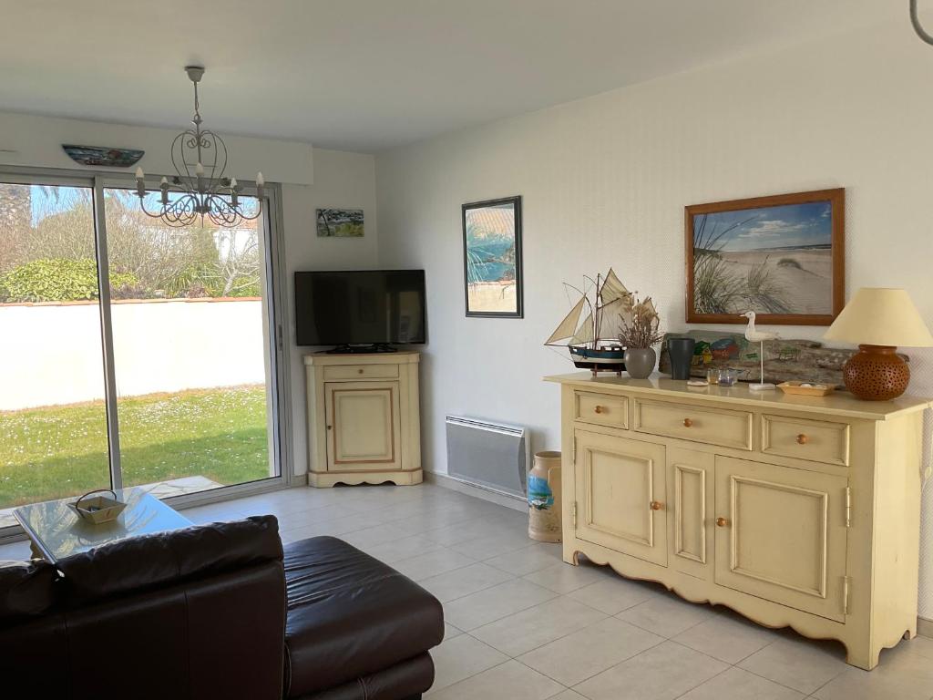 a living room with a couch and a tv at Maison bercée par le bruit de la mer île de ré in Sainte-Marie-de-Ré