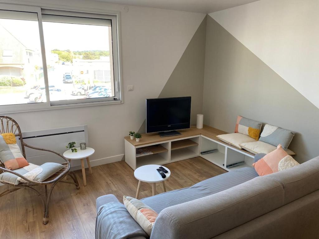 un salon avec un canapé et une télévision dans l'établissement L'APPART, proche mer et centre-ville, rénové en 2021, à Neufchâtel-Hardelot