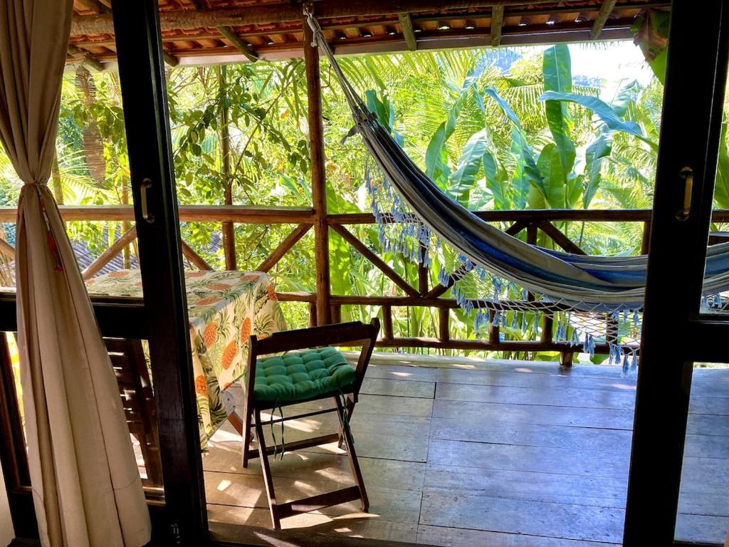 パラチにあるEco Lodge in nature -10 min to Paraty centerlのハンモックと椅子付きのポーチが備わる客室です。