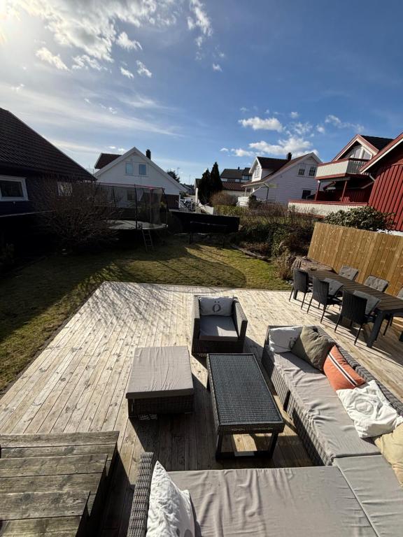a patio with benches and tables on a wooden deck at Romslig familiehus på Sørlandskysten in Kristiansand
