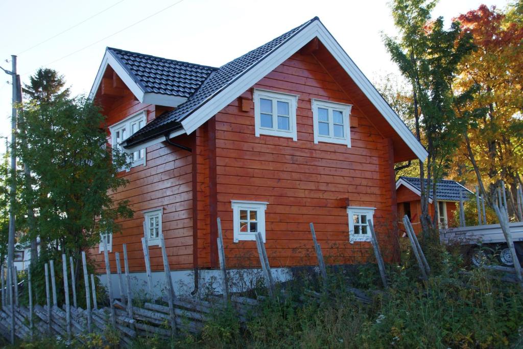 a red house with a black roof and white windows at Aaroybukt Guesthouse in Årøybukta