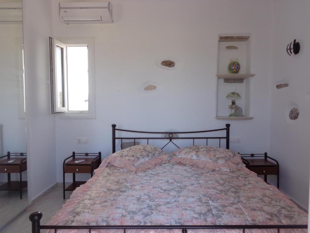 a bed in a white bedroom with two tables at Antiparos Diamond in Antiparos