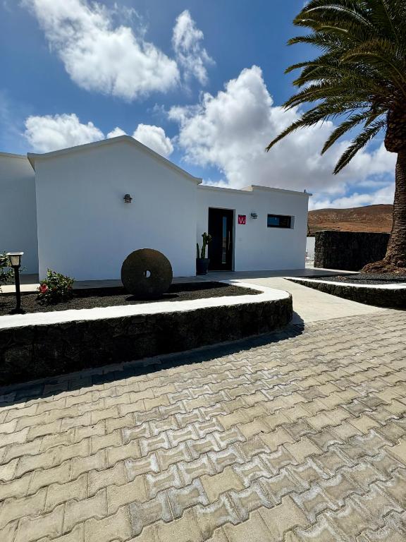 a white building with a palm tree in front of it at Sombra de Guanapay in Teguise