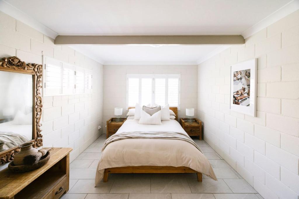 Merduka Sands 4 - Cozy charming cottage في Brooms Head: غرفة نوم بها سرير كبير ومرآة