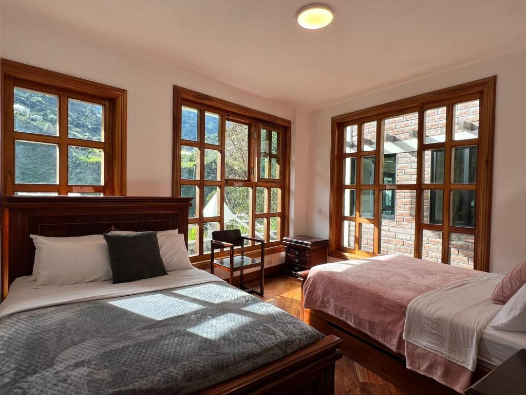1 dormitorio con 2 camas y ventanas grandes en Villa Pastaza 4 Bedroom 3 Bath, en Baños
