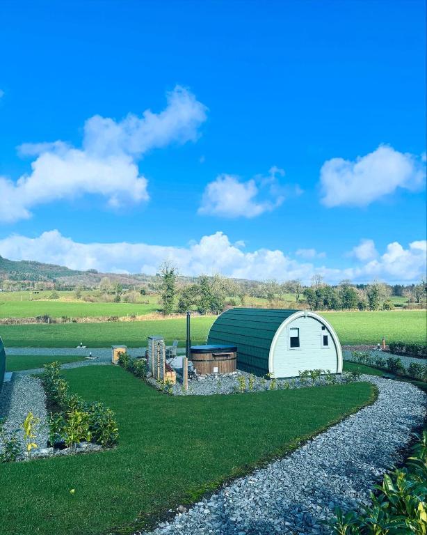 a garden with a white shed and a gravel driveway at Knockmany View Glamping in Augher