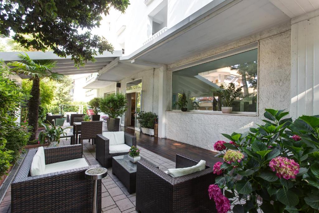 an outdoor patio with chairs and tables and flowers at Hotel Gianlore in Milano Marittima