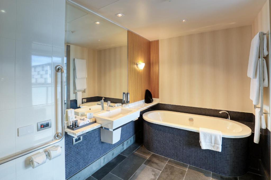a bathroom with a tub and two sinks and a mirror at Marsden Viaduct in Auckland