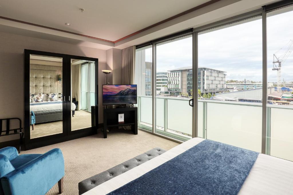 a bedroom with a bed and a tv and windows at Marsden Viaduct in Auckland