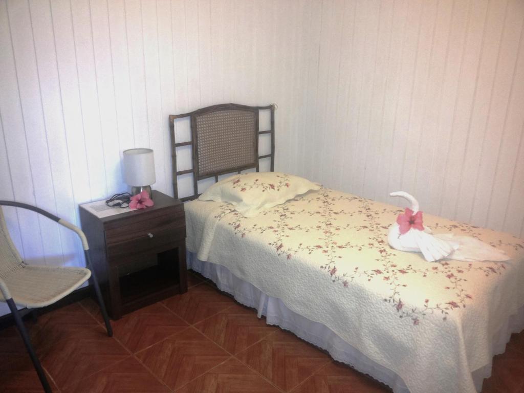 a bedroom with a bed with a dresser and a nightstand at Tupa Hotel in Hanga Roa