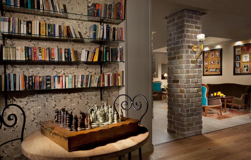 una habitación con un tablero de ajedrez en una mesa frente a un estante de libros en Shtarkman Erna Boutique Hotel Nahariya, en Nahariyya