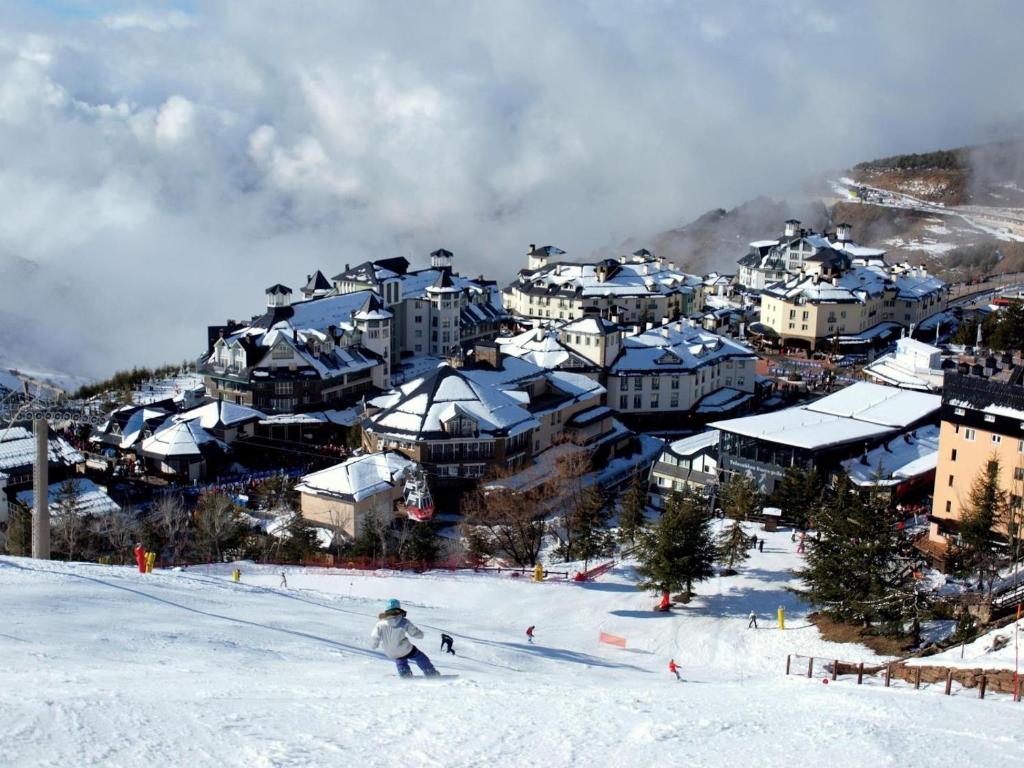 osoba jeździ na nartach po pokrytej śniegiem górze w obiekcie Apartamento w mieście Sierra Nevada