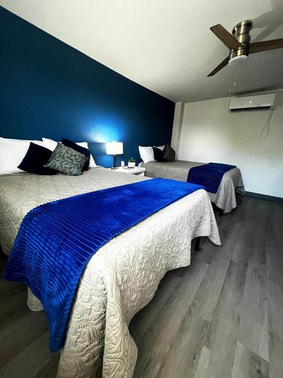 a bedroom with two beds and a blue wall at AXEL Suites Departamento 1A in Delicias