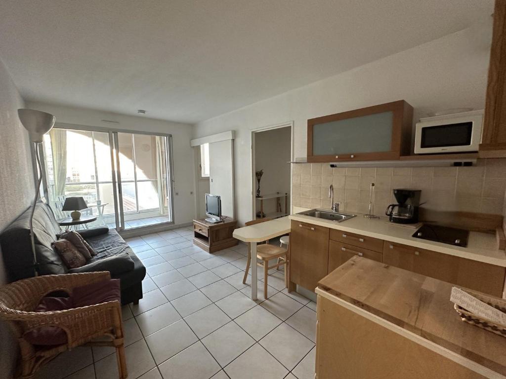 une cuisine et un salon avec un canapé et une table dans l'établissement Charmant T2 avec loggia, proche plage, résidence avec piscine - FR-1-472-209, à Sète