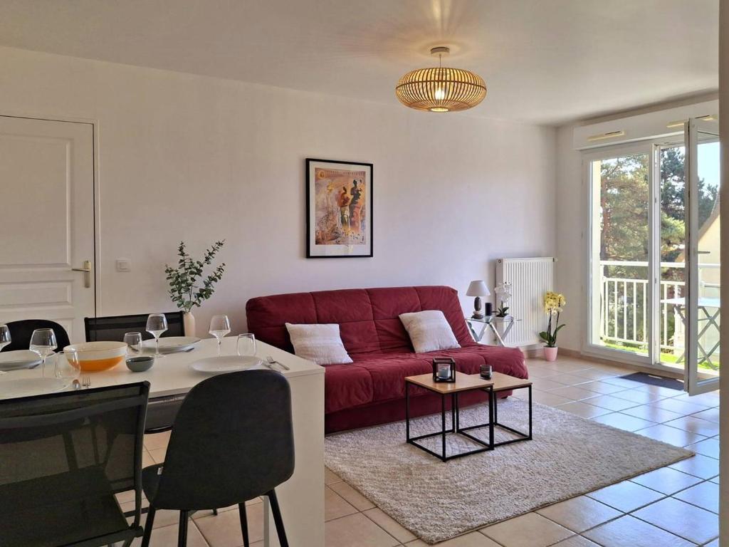 un salon avec un canapé rouge et une table dans l'établissement Charmant cocon avec WiFi à Merville-Franceville-Plage - FR-1-788-59, à Merville-Franceville-Plage