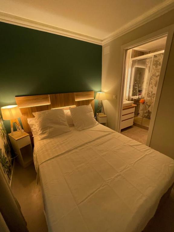 - une chambre avec un grand lit blanc et un mur vert dans l'établissement Azuria, à Cannes