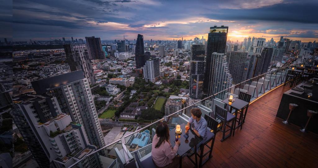 two people sitting on a balcony of a city skyline at Bangkok Marriott Hotel Sukhumvit in Bangkok