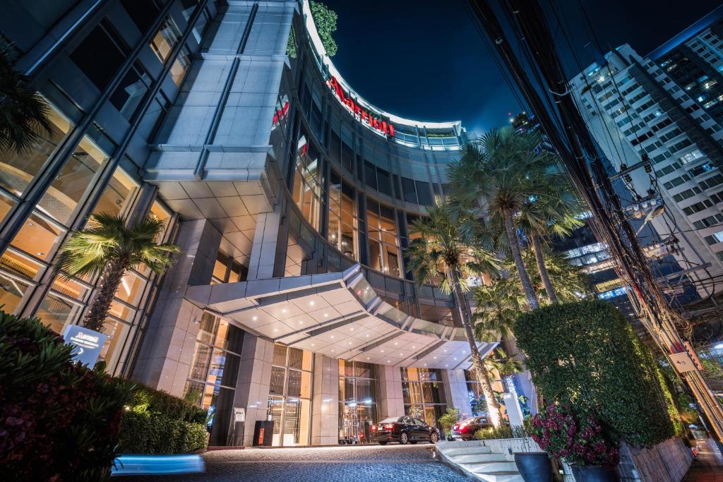 a tall building with palm trees in front of it at Bangkok Marriott Hotel Sukhumvit in Bangkok