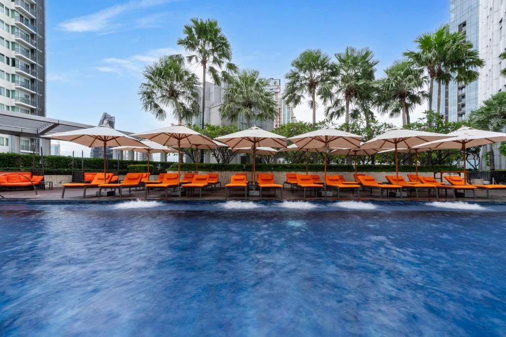 a swimming pool with orange chairs and umbrellas at Bangkok Marriott Hotel Sukhumvit in Bangkok