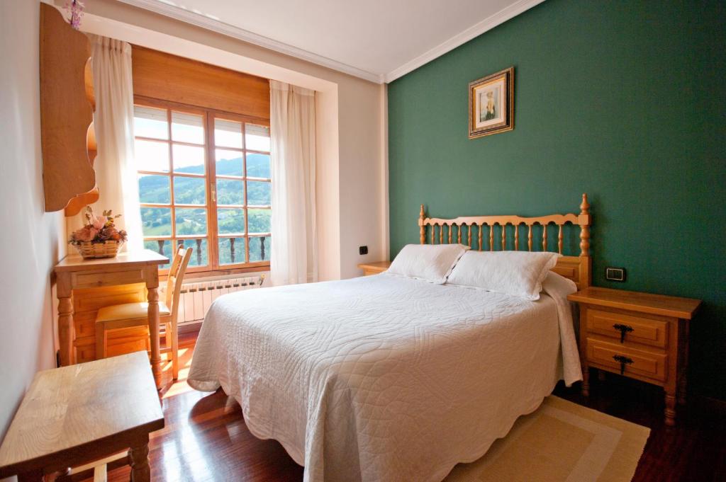 1 dormitorio con 1 cama con pared verde en Apartamentos Casa Paulino, en Taramundi