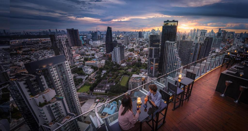 two people sitting on a balcony of a city skyline at Bangkok Marriott Hotel Sukhumvit in Bangkok