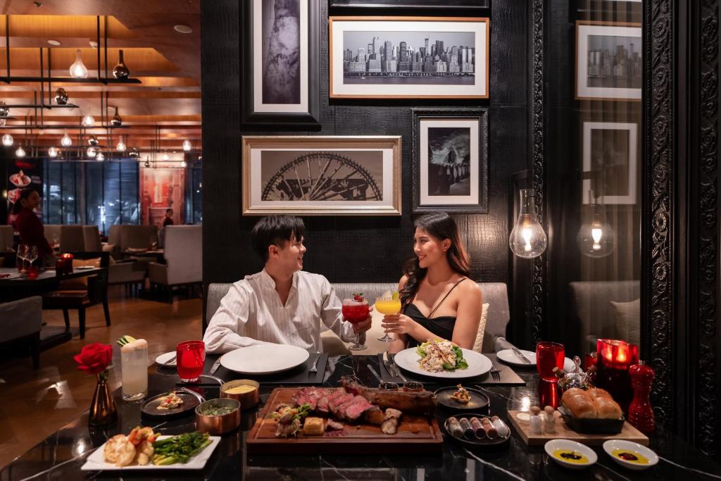 a man and woman sitting at a table with food at Bangkok Marriott Hotel Sukhumvit in Bangkok