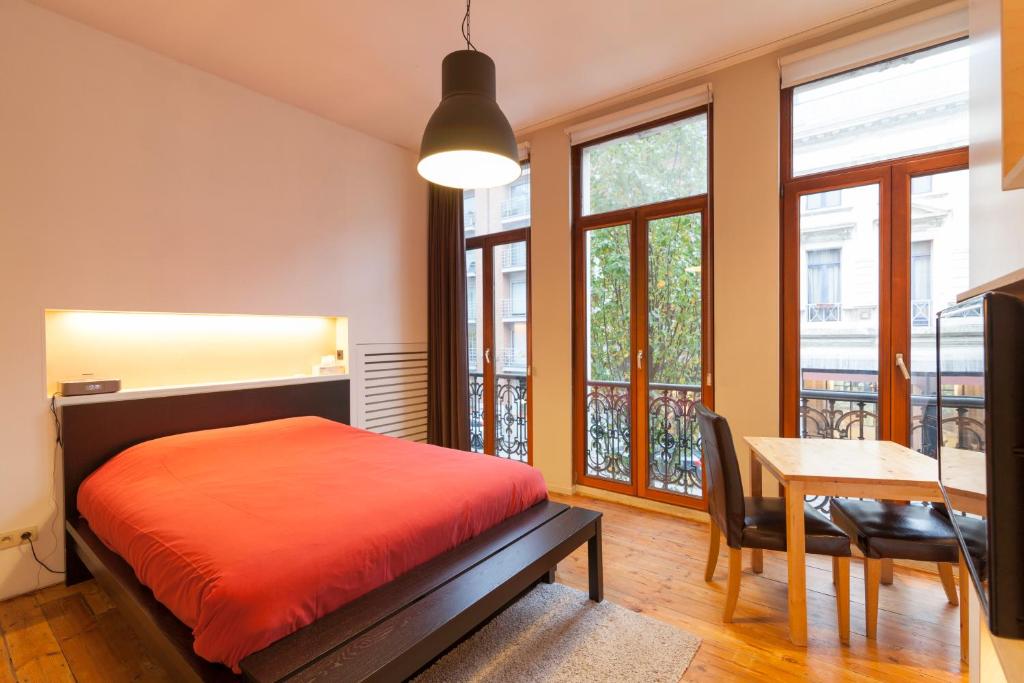 een slaapkamer met een bed en een tafel en ramen bij Because the Night city lodge in Antwerpen