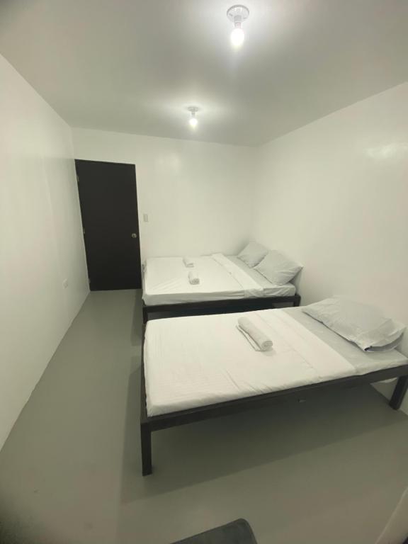two beds sitting in a white room with at Inn Convenience in Coron
